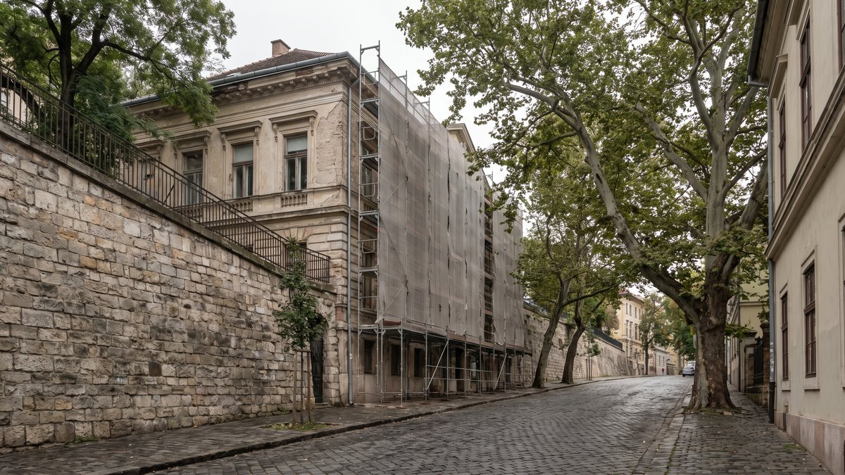 Állványozott, felújítás alatt álló villa a budai Várnegyed szűk, macskaköves utcájában, kőtámfal mellett